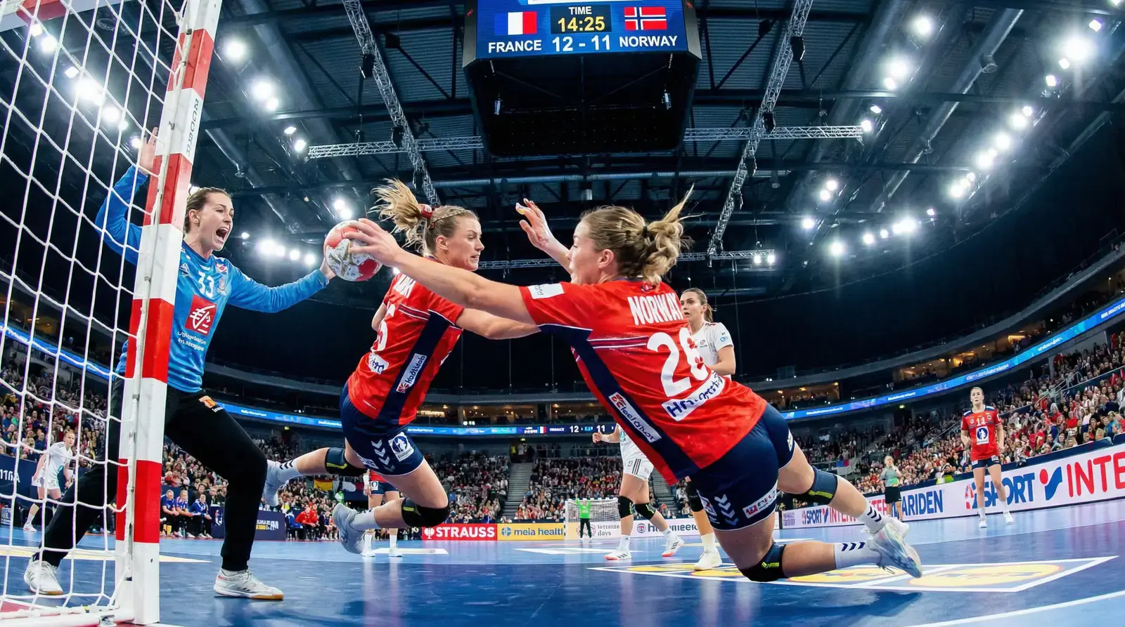 Jogadoras de andebol feminino em ação durante jogo oficial com bola e baliza